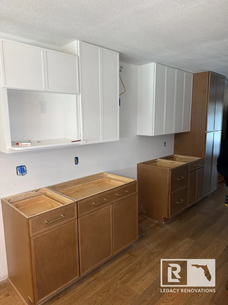 In-progress kitchen renovation in Jacksonville, FL showing newly mounted white upper cabinets and natural wood base cabinets awaiting countertops.