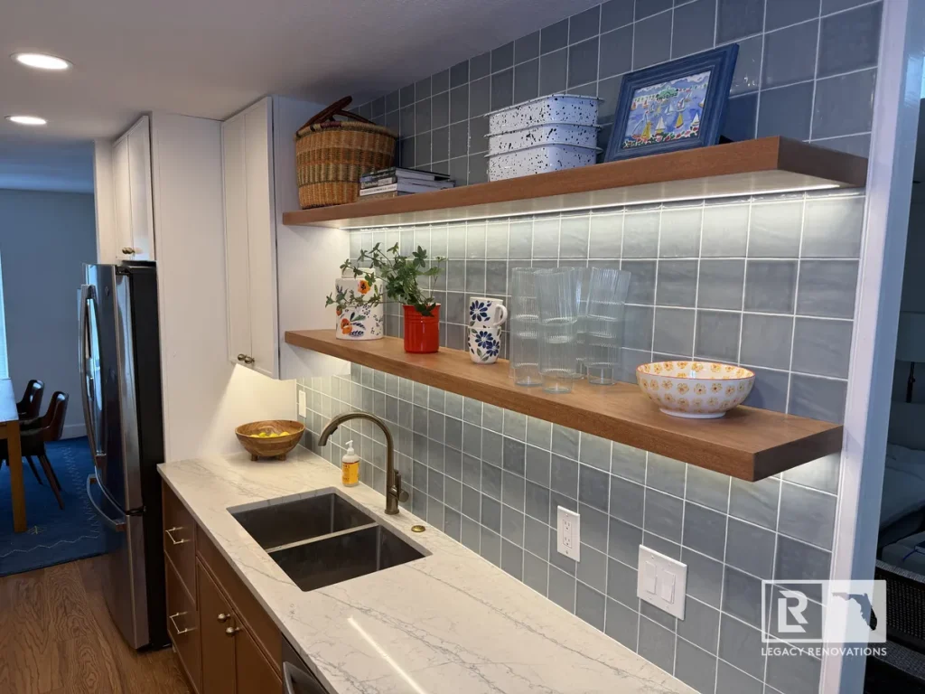 Floating wood shelves with LED strip lighting mounted on a glossy blue tile backsplash in a Jacksonville, FL kitchen.
