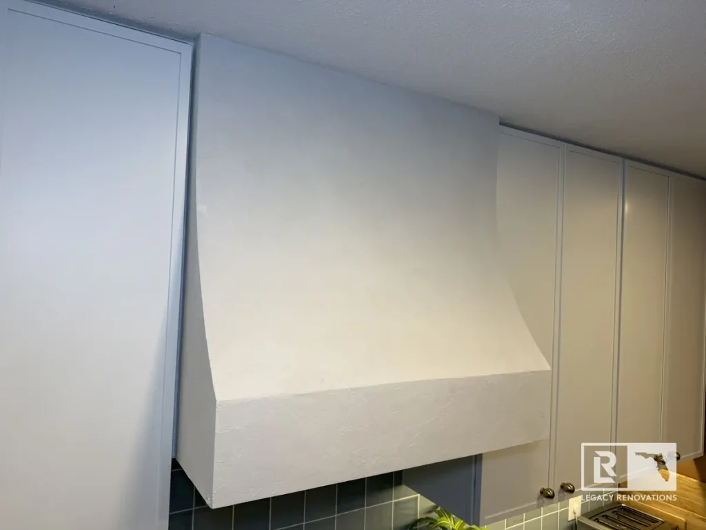 Curved plaster range hood installed between modern light grey kitchen cabinets in a Jacksonville, FL home remodel.