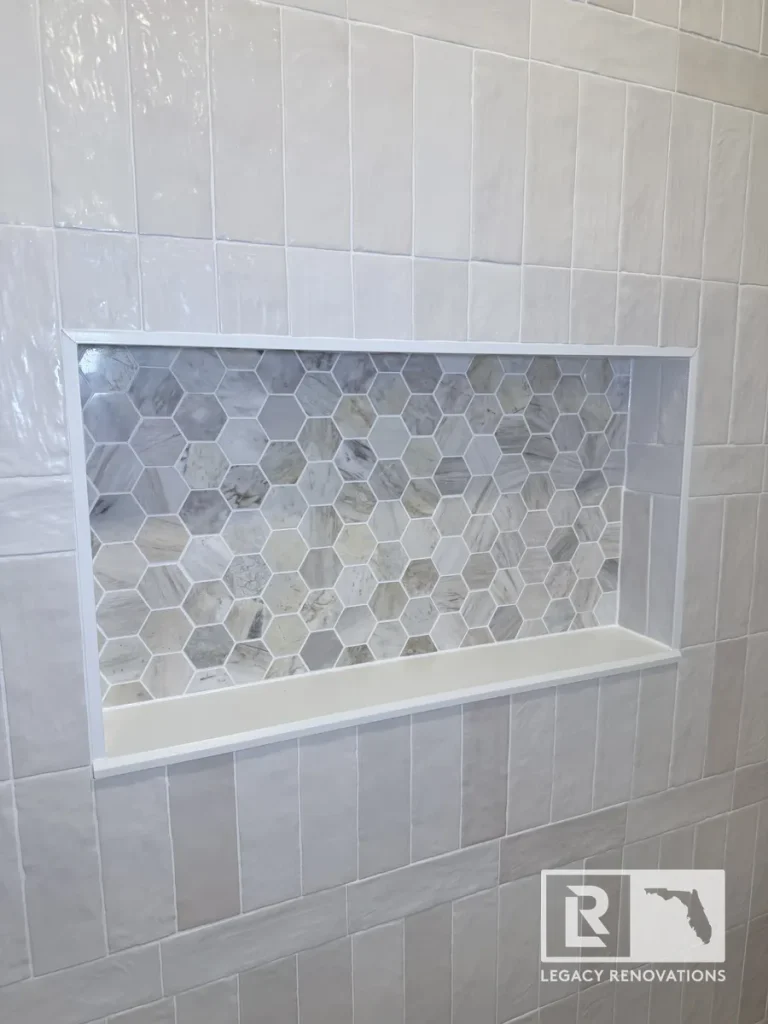 Rectangular inset shower shelf framed by off-white vertical subway tiles with a stone honeycomb pattern inset in Mandarin Jacksonville FL.