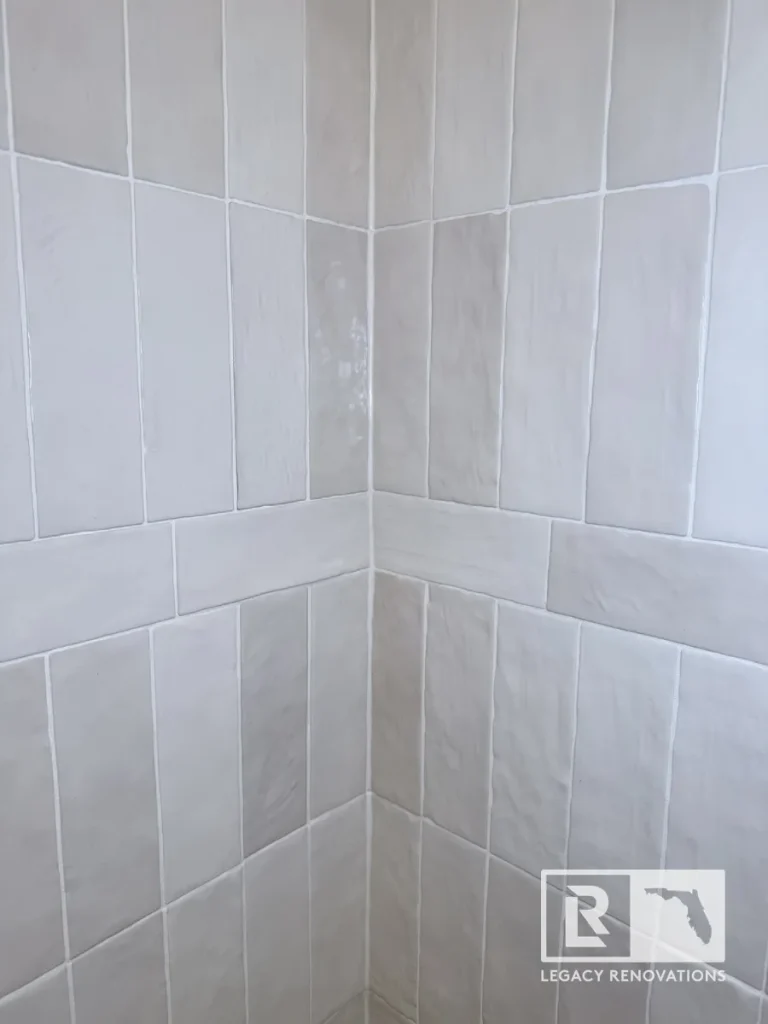 Close-up of a 90-degree shower wall corner with off-white vertical subway tiles and white grout in a Mandarin Jacksonville FL home.