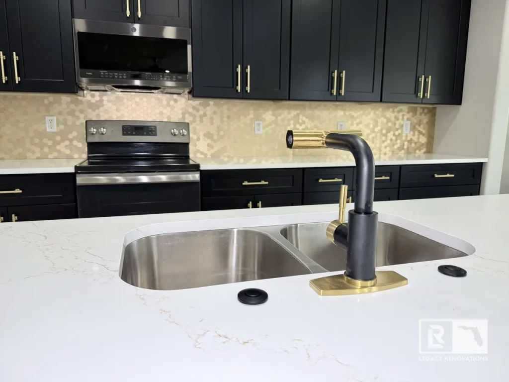 Black and gold kitchen faucet installed on a dual-basin stainless steel undermount sink.